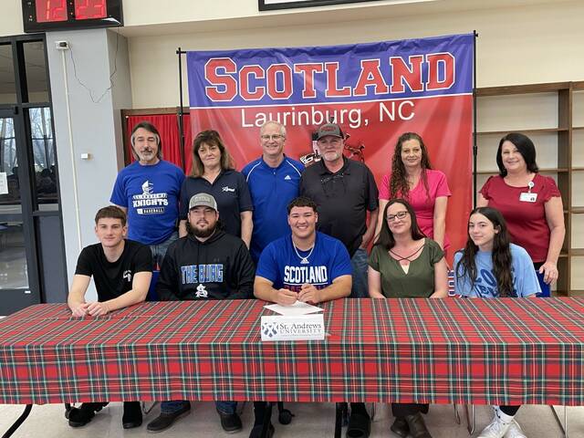 129479322_web1_Micah
Scotlands Micah Clark (center, bottom row) takes a picture with his family and Scotland head coach Richard Bailey (third from left, top row) after he signed to play college football at St. Andrews University Friday afternoon.
Photo| Brandon Hodge/ The Laurinburg Exchange