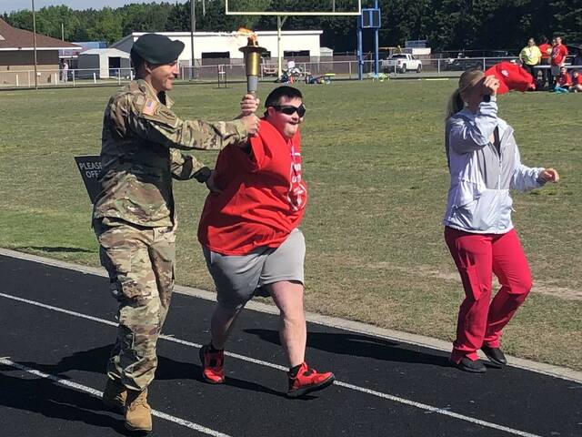 130566348_web1_thumbnail_IMG_3718
Special Olympics athlete Devon Martin, center, relays the Olympic torch with Army Master Sergeant Shawn Edwards, left, before the start of the 43rd Special Olympics of Scotland County on Wednesday at Pate Stadium in Laurinburg.
Stephanie Walcott | For the Exchange