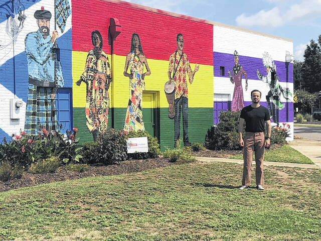 130745867_web1_thumbnail_IMG_3962
Marcus Dunn is shown standing before his completed mural on the side of the Church Community Services building facing Atkinson Street. The mural is divided into three panels and portrays Scottish, African American, and Native American people in their traditional garb.