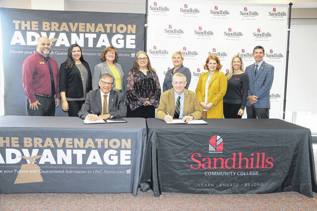 131052012_web1_Sandhills_CC_UNCP_MOU_251816
From UNCP, standing left to right, are Chris Hunt, Jamee Hunt Freeman and Kelly Brennan; and from SCC, are Rebecca Roush, Michelle Bauer, Julie Voigt, Cary Green and Chad Williams. Seated from left to right: UNCP Chancellor Robin Gary Cummings and SCC President Sandy Stewart during a signing ceremony.
Courtsy photo