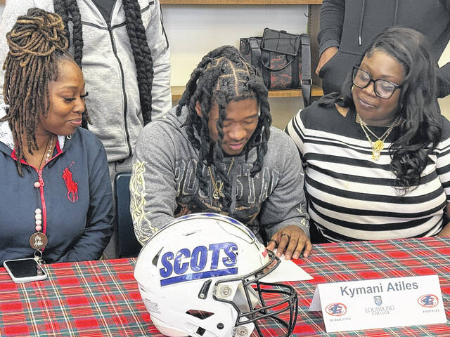 Kymani Atiles, center, signs his letter of intent to attend Louisburg College on March 13, 2026. 
                                 Travis Petty Jr | The Laurinburg Exchange