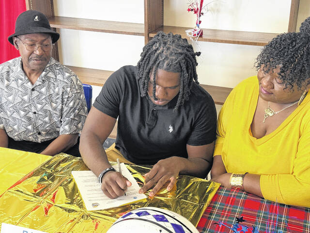 Scotland senior RJ Bethea, center, signs his letter of intent to attend Averett University, joined by his mother and family on March 27, 2026. 
                                 Travis Petty Jr | The Laurinburg Exchange