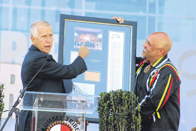 U.S. Sen. Thom Tillis, left, presents Lumbee Tribal Chairman John Lowery, right, with the roll call vote tally from the Senates passage of the National Defense Authorization Act, which included the Lumbee Fairness Act, on Dec. 17, 2025, during the Lumbee Tribes Federal Recognition Celebration Saturday in Pembroke.
                                 Chris Stiles | The Robesonian